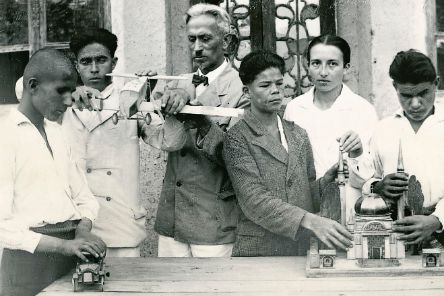 Ein Mann, eine Frau und einige Jugendliche betasten ein Flugzeugmodell und das Modell  eines Gebäudes