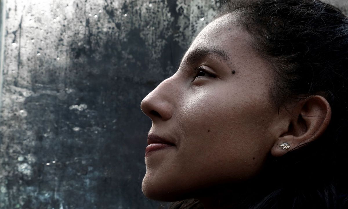 Lächelnde Frau im Profil vor einer Glasscheibe voller Wassertropfen