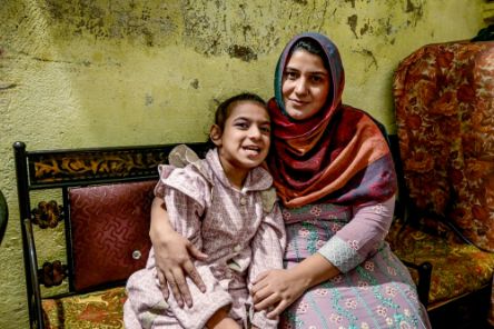 A mother and her intellectual and physical disabled daughter sitting on a bench